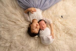 Big sister laying down holding baby brother